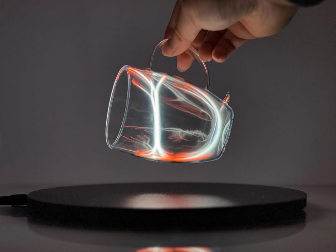 Plasma Mug by Astro Labs glowing with white plasma filaments inside a clear double-walled glass mug held over a powered base.
