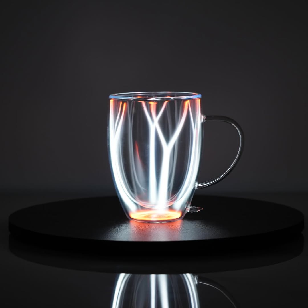 Plasma Mug by Astro Labs glowing with white plasma filaments inside a clear double-walled glass mug on a powered base.